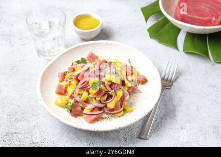 Nourriture, nourriture, salade tropicale de thon tahitien de mangue sur assiette blanche sur feuille de monstera tropicale Banque D'Images