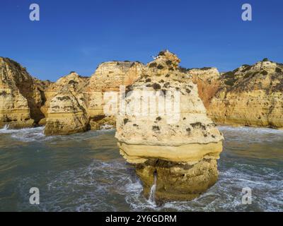 Vue aérienne sur les falaises rocheuses et les vagues près de Praia da Marinha dans l'Algarve, Portugal, Europe Banque D'Images