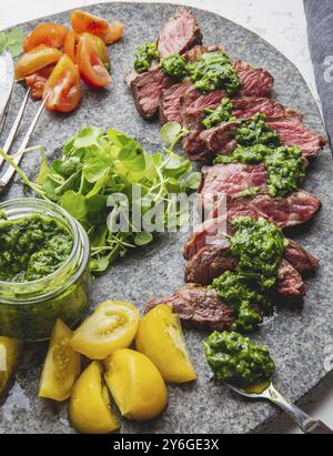 Nourriture, tranches de steak de bœuf avec sauce chimmichuri sur assiette de pierre grise Banque D'Images