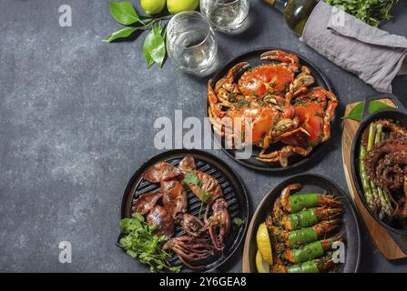 Photographie culinaire, table avec plats de fruits de mer, crabes cuits, crevettes tigrées, poulpe grillé et calmars sur une poêle en fonte Banque D'Images