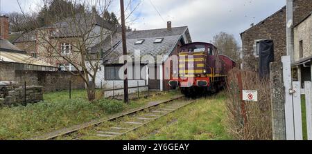 Viroinval, Belgique, décembre 2021 : locomotive de train arrivant dans une ruelle étroite entre des maisons à Viroinval, Europe Banque D'Images