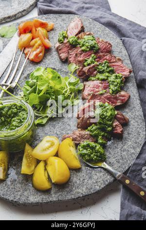 Nourriture, tranches de steak de bœuf avec sauce chimmichuri sur assiette de pierre grise Banque D'Images