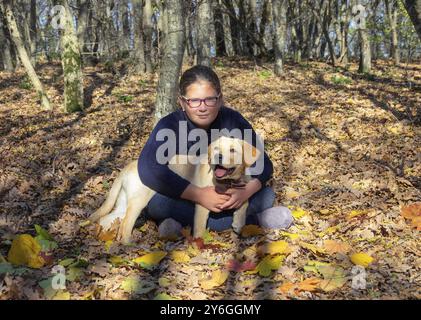 Portrait d'une fille avec un chiot chien de race Labrador Retriever dans la forêt d'automne Banque D'Images