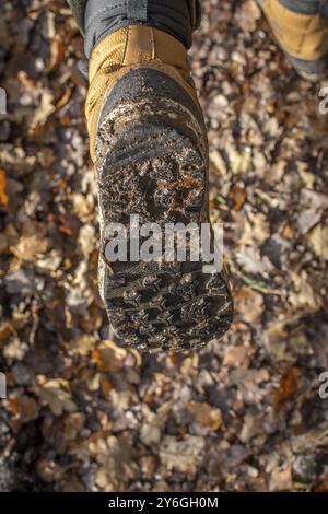 Plan vertical de bottes de randonnée marron ou beige lors d'une promenade dans la forêt boueuse d'automne Banque D'Images