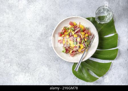 Nourriture, nourriture, salade tropicale de thon tahitien de mangue sur assiette blanche sur feuille de monstera tropicale Banque D'Images