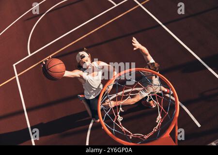 Score ! Vue de dessus d'un jeune homme en vêtements de sport marquant un slam dunk tout en jouant au basket-ball en plein air Banque D'Images