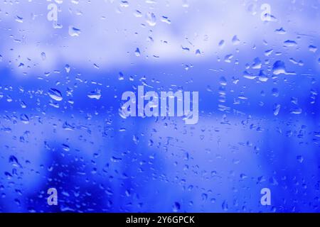 Gouttes de pluie sur une fenêtre, illustrant le temps gris et pluvieux pendant la journée. Niveaux de gris noir et blanc Banque D'Images