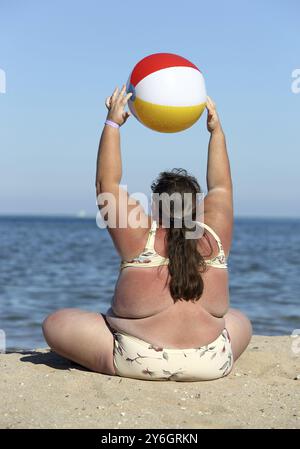 Femme en surpoids faisant de la gymnastique avec balle sur la plage Banque D'Images