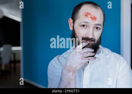 Portrait de l'acteur dépeignant le personnage de zombie dans le film d'horreur, se préparant pour le rôle sur le plateau. Homme habillé comme une créature morte-vivante pour le prochain film de thriller, portant un faux maquillage de plaies de sang Banque D'Images