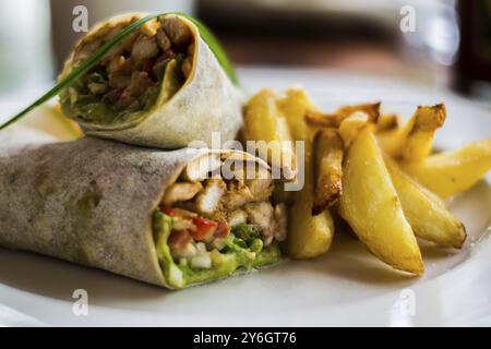 Des roulés savoureux avec du poulet, de l'avocat, de la laitue et des frites sur une assiette. Mise au point sélective Banque D'Images