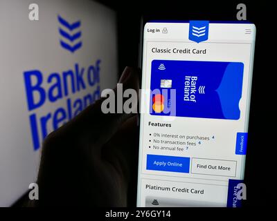 Dans cette illustration photo, une personne tient un smartphone avec la page Web de la société financière irlandaise Bank of Ireland Group plc devant le logo. Banque D'Images