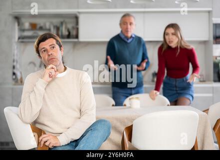 Père et femme grondent un homme. Il ne veut pas leur parler. Querelle familiale Banque D'Images