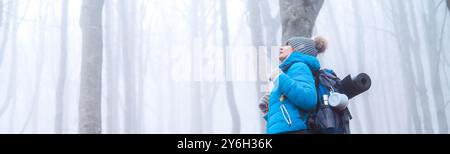 Vue de côté d'une femme randonneuse randonnant dans les montagnes respirant l'air frais dans une forêt brumeuse en hiver - concept de voyage d'hiver Banque D'Images