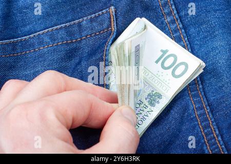 Homme mettant des billets de banque en zloty polonais dans la poche Banque D'Images