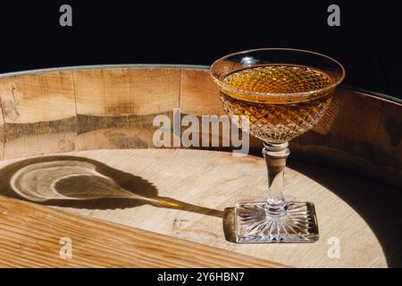 cocktail de whisky ambré en verre coupe hobnail vintage sur tonneau en bois au soleil Banque D'Images