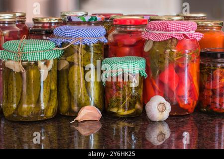 Bocaux en verre avec concombres marinés (cornichons), poivrons rouges marinés, tomates séchées au soleil. Bocaux de divers légumes marinés. Aliments en conserve pour l'hiver, Banque D'Images