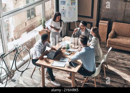 En passant en revue les détails. Vue de dessus de la jeune femme moderne effectuant la présentation tout en travaillant avec des collègues dans le bureau Banque D'Images