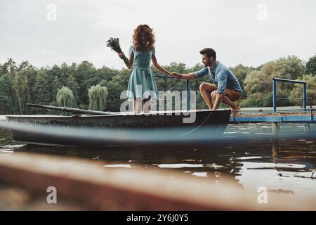 Belle journée ensemble. Heureux jeune couple se préparant à ramer un bateau tout en profitant de leur date à l'extérieur Banque D'Images