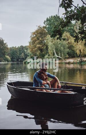 Laisser les soucis derrière. Beau jeune couple embrassant et souriant tout en profitant de la date romantique sur le lac Banque D'Images