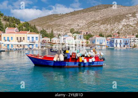 Un bateau avec de nombreuses défenses et beaucoup de plastique vide utilisés comme défenses et maisons traditionnelles multicolores et colorées en bord de mer à Kastellorizo ​​island, Dodekan Banque D'Images