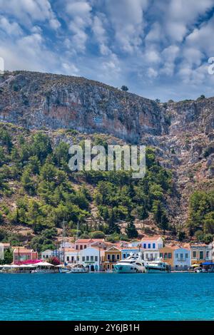 Maisons traditionnelles multicolores et colorées en bord de mer et drapeau grec peints sur des rochers sur une colline à Kastellorizo ​​island, Dodekanisos, Grèce Banque D'Images