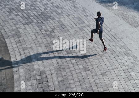 Garder la forme au sérieux. Vue de dessus du jeune homme africain dans les vêtements de sport jogging tout en faisant de l'exercice à l'extérieur Banque D'Images