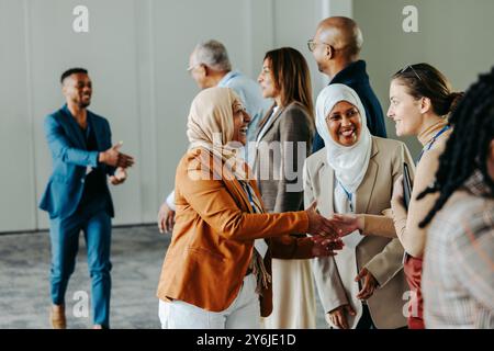 Un groupe de professionnels divers échangeant volontiers des poignées de main et des salutations lors d'une conférence d'affaires dynamique, favorisant les connexions et le réseautage op Banque D'Images