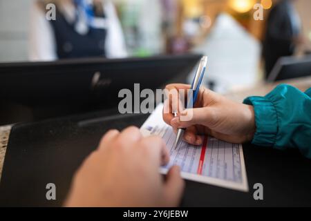 Berlin, Allemagne. 25 septembre 2024. ILLUSTRATION - Une femme remplit un formulaire d'inscription d'hôtel dans un hôtel. À partir de l'année prochaine, l'obligation d'inscription à l'hôtel sera supprimée, au moins pour les clients allemands. Crédit : Sebastian Gollnow/dpa/Alamy Live News Banque D'Images