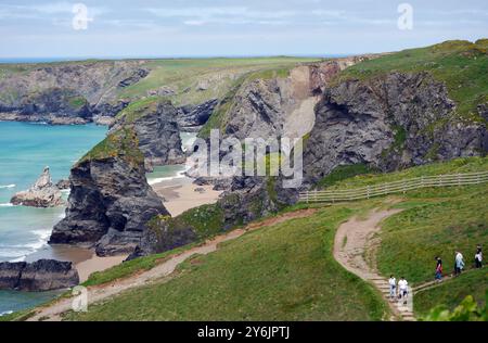 Touristes / vacanciers marchant sur le chemin vers Carnewas point de Bedruthan Steps (Sea Stacks) sur le sentier côtier du Sud-Ouest, Cornouailles du Nord, Angleterre, Royaume-Uni. Banque D'Images