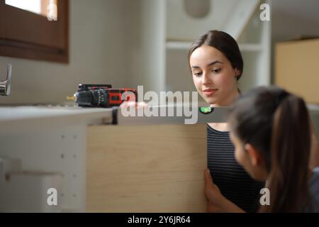 Colocataires réformant la maison nivelant la porte de meubles dans la cuisine Banque D'Images