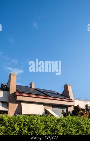 détail d'une grande maison surmontée d'arbres et de plantes avec une installation de panneaux solaires photovoltaïques pour exploiter l'énergie du soleil. urbani durable Banque D'Images