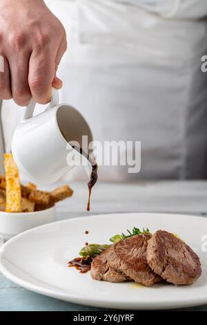 Filet de bœuf grillé avec sauce demi-glace et légumes grillés sur une assiette en porcelaine blanche Banque D'Images