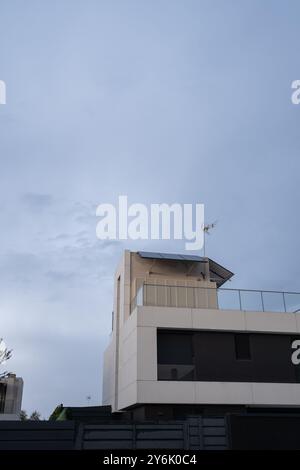 Détail du toit d'un chalet individuel à l'architecture avant-gardiste. Il a des panneaux solaires photovoltaïques, le ciel est gris et nuageux. Décarbonisation Banque D'Images