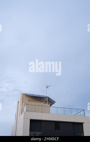 Détail du toit d'un chalet individuel à l'architecture avant-gardiste. Il a des panneaux solaires photovoltaïques, le ciel est gris et nuageux. Décarbonisation Banque D'Images