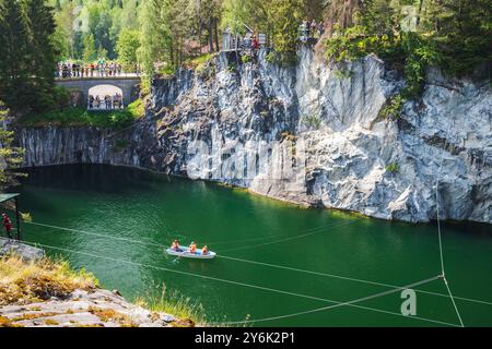 Ruskeala, Russie - 12 juin 2021 : paysage carélien. Ancienne carrière de marbre remplie d'eau souterraine. Les touristes sont dans des bateaux et sur une côte rocheuse Banque D'Images