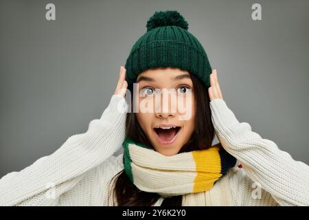 Une jeune femme dans un chapeau confortable et une écharpe exprime l'excitation avec un look surpris. Banque D'Images