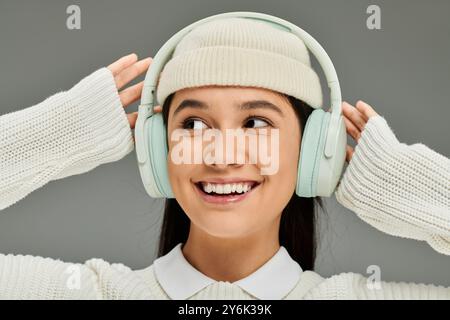 Une jeune femme élégante sourit largement, appréciant ses morceaux préférés avec un casque. Banque D'Images