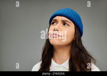 Une jeune femme habillée avec style affiche un comportement expressif et contemplatif au milieu de tons subtils. Banque D'Images