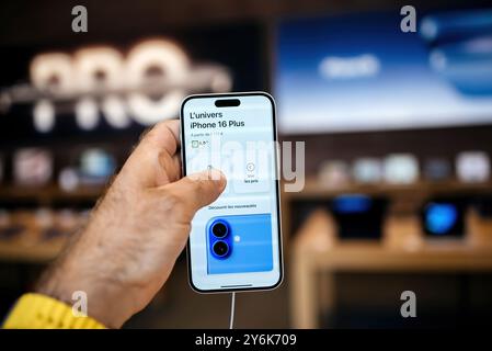 Paris, France - 20 septembre 2024 : un client masculin détient le dernier smartphone iPhone 16 plus dans un Apple Store avec des bannières promotionnelles défocalisées dans le Banque D'Images