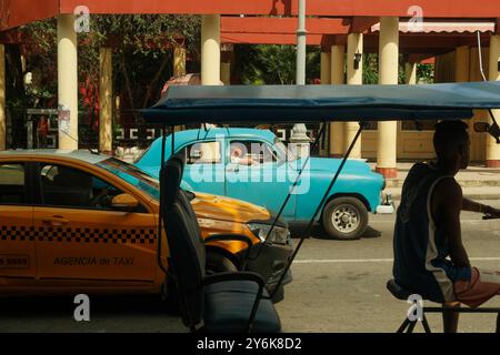 Vieille Havane, Cuba 2024 avr 01 transport commun à Cuba. Tricycle de rue bici taxis, taxis jaunes appartenant à l'État, et voitures anciennes attendant à la circulation Banque D'Images