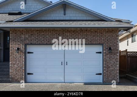 Porte de garage. Maison moderne avec porte de garage blanche qui est fermée. Un quartier parfait. Maison familiale avec large porte de garage et allée en béton en f Banque D'Images