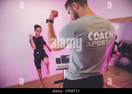 Femme aux cheveux foncés dans la trentaine faisant de l'électrostimulation EMS avec un entraîneur sportif Banque D'Images