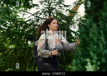 Une femme de grande taille marche à travers un feuillage vibrant profitant de son temps à l'extérieur. Banque D'Images