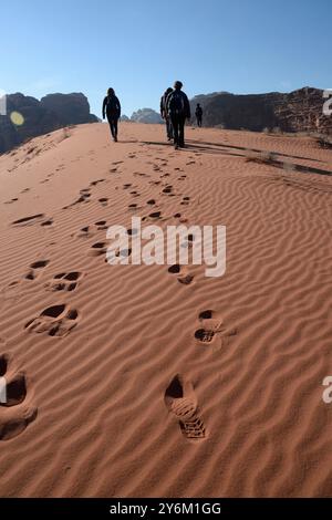 Jordanie, moyen-Orient, désert de rhum Wadi, un groupe de randonneurs européens marchent dans le sable et laissent leurs empreintes derrière eux Banque D'Images