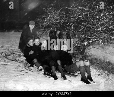 Enfants traînant dans la neige portant l'uniforme scolaire 1947 Banque D'Images