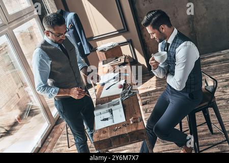 En passant en revue les détails. Vue de dessus de jeunes designers à la mode discutant du travail tout en passant du temps dans l'atelier Banque D'Images