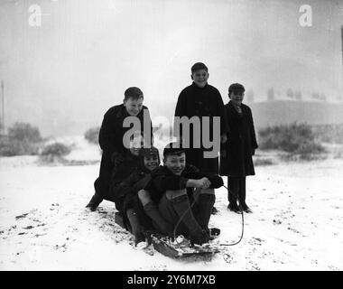 Enfants traînant dans la neige portant l'uniforme scolaire 1947 Banque D'Images