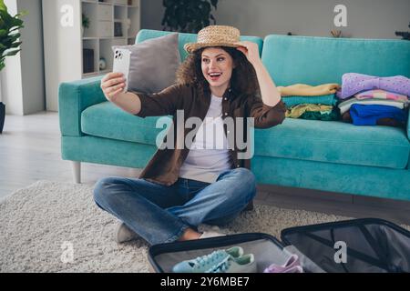 Photo de jeune femme drôle autoportrait portant chapeau de touriste posant dans de nouveaux vêtements pour le voyage de week-end à l'intérieur loft maison moderne Banque D'Images