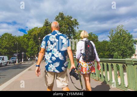France, ile-de-France, Paris. Couple senior, l'homme avec un appareil photo et une chemise hawaïenne. Banque D'Images