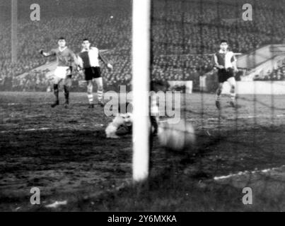 Tommy Taylor (extrême gauche), l'attaquant central de Manchester United, regarde son entraînement bas battre Carmelo, gardien de but à l'Atletico de Bilbao (Espagne) et entrer dans le filet juste à l'intérieur du poteau pour le deuxième but de Manchester dans la deuxième manche du quart de finale de la Coupe d'Europe de Football du club à Manchester ce soir (mercredi, Manchester United a gagné 3 à 0. Bilbao 5 - 3, Manchester sortent victorieux du quart de finale avec un agrégat de 6 -5. 6 février 1957 Banque D'Images